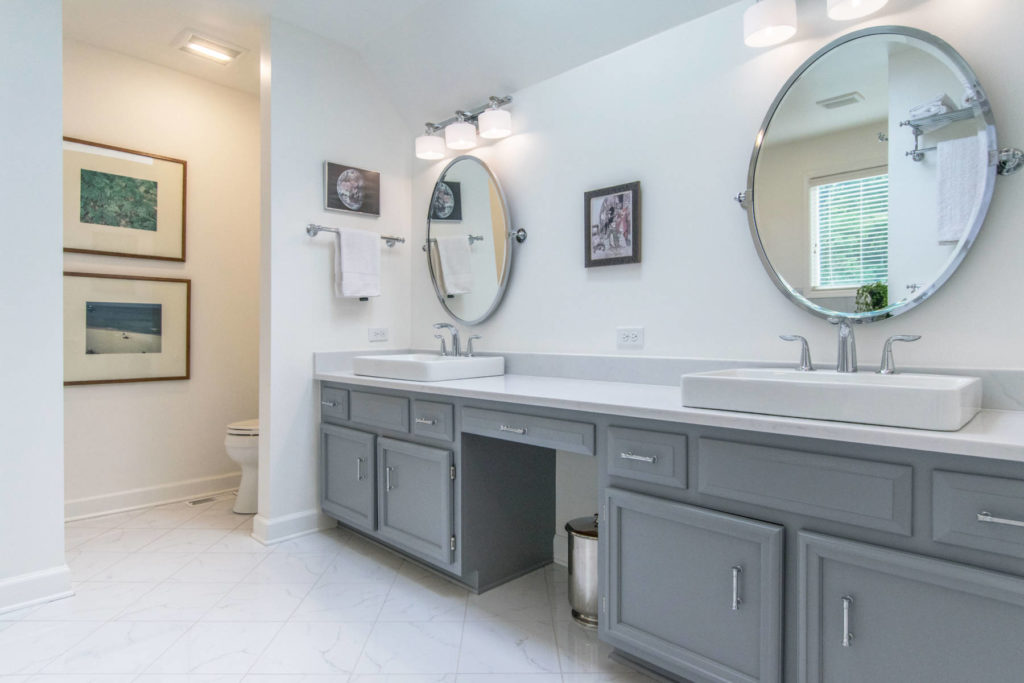 A bathroom with dual vanity and sink and mirror on the wall and white floor 