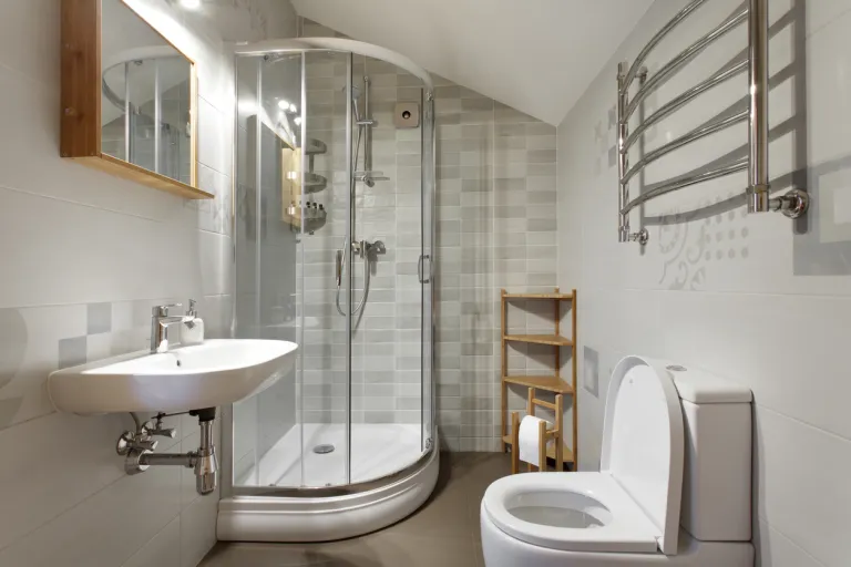 A bathroom with bath area and toilet and wooden storage area 
