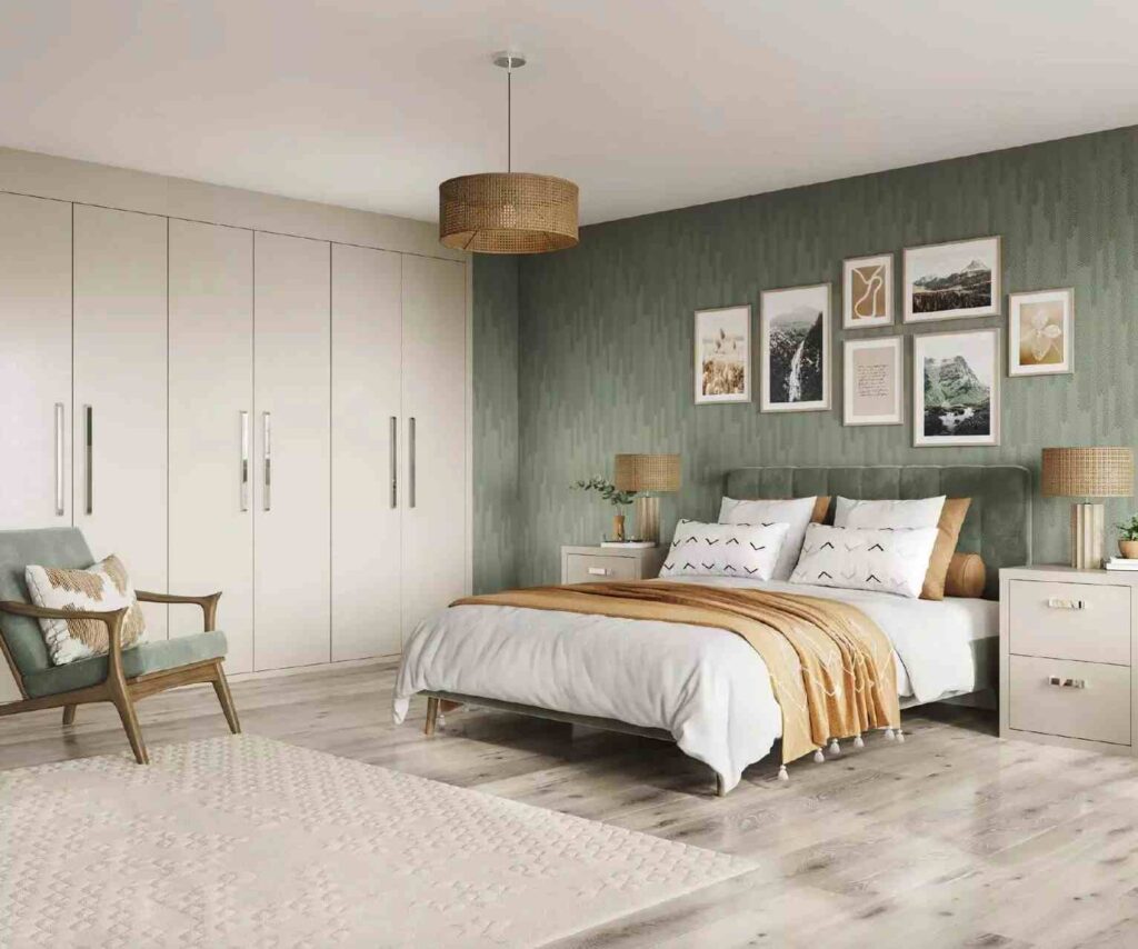 A sage and cream bedroom with frames on the wall and chair in the room 