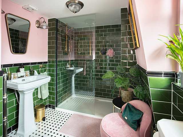 A pink and green bathroom with glass shower and pink chair in the bathroom