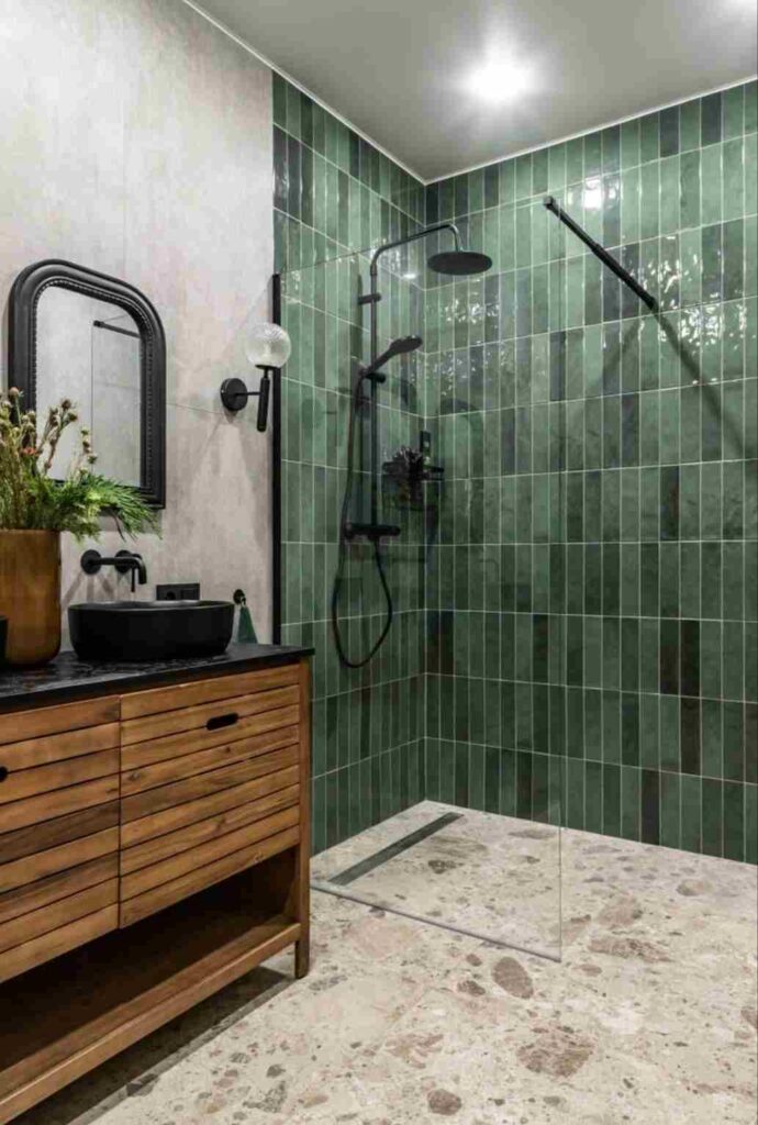 A green bathroom with subway tiles and wooden vanity and mirror on the wall 