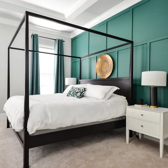 A green and grey bedroom with black bed and white nightstand and green curtains with black rod 