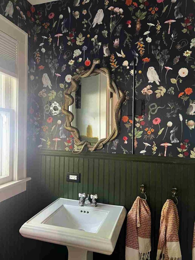 A green bathroom with black wallpaper and mirror on the wall 
