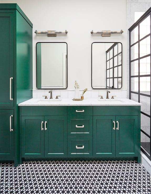 A green vanity with black and white mosaic tiles and mirrors on the wall 