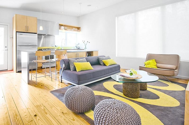 A white living room with grey and yellow accents and wooden floor and rug on it
