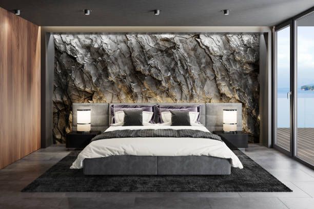 A bedroom with stone wall and whit bed and wooden floor 