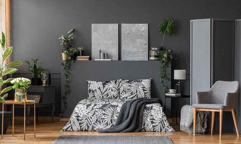 A grey bedroom with plants in the bedroom and wooden floor and rug on it 