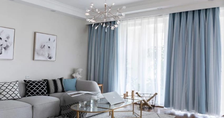 A grey living room with blue curtain and grey sofa and glass table 