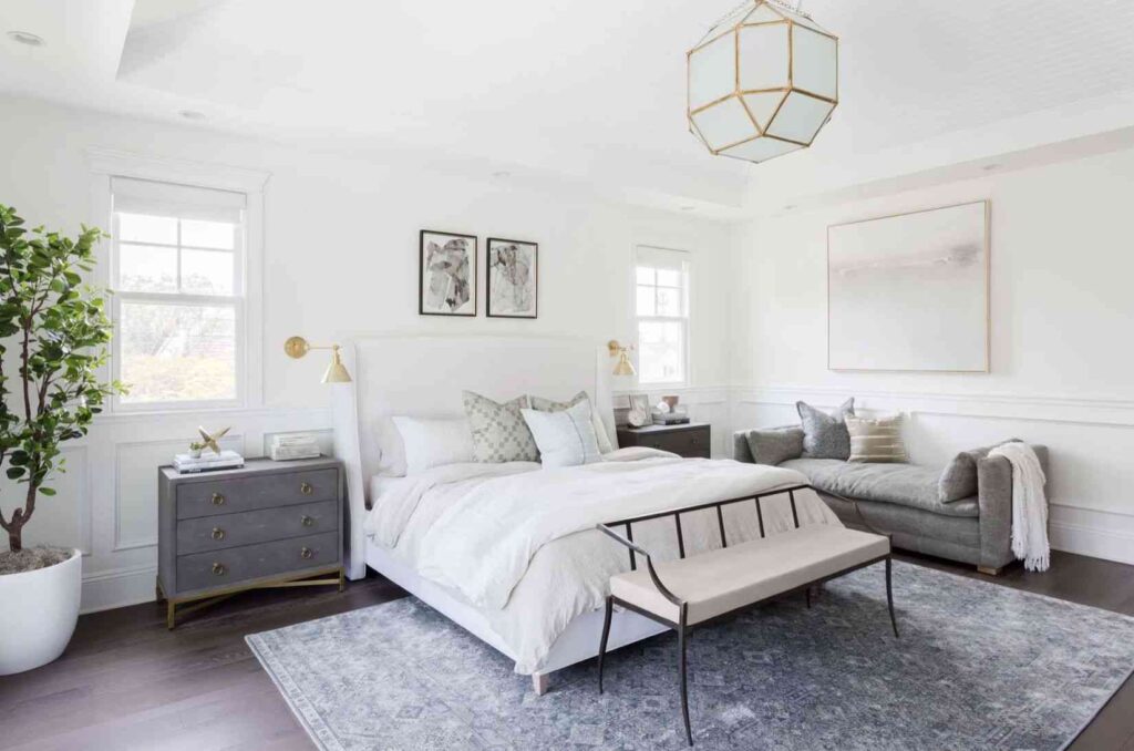 A white bedroom with grey nightstand and wooden floor and rug on it 