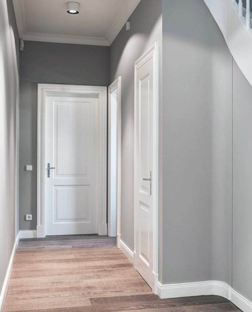 A grey walls with white door and wooden floor 