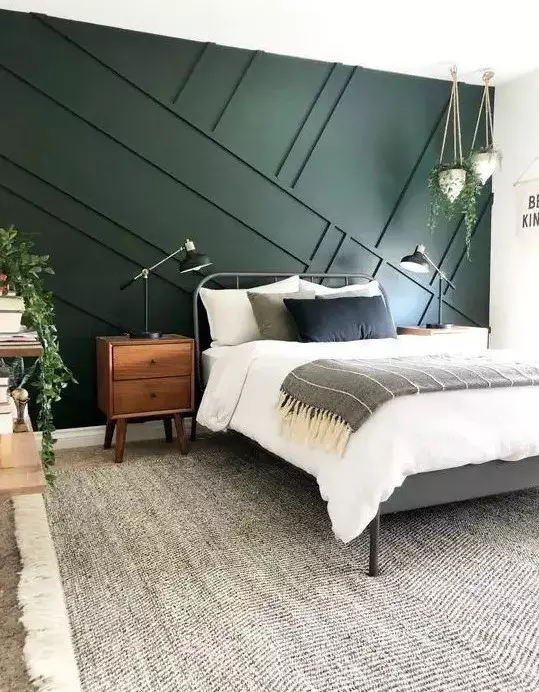 A geometric green wall in bedroom with wooden nightstand and wooden floor and rug on it 