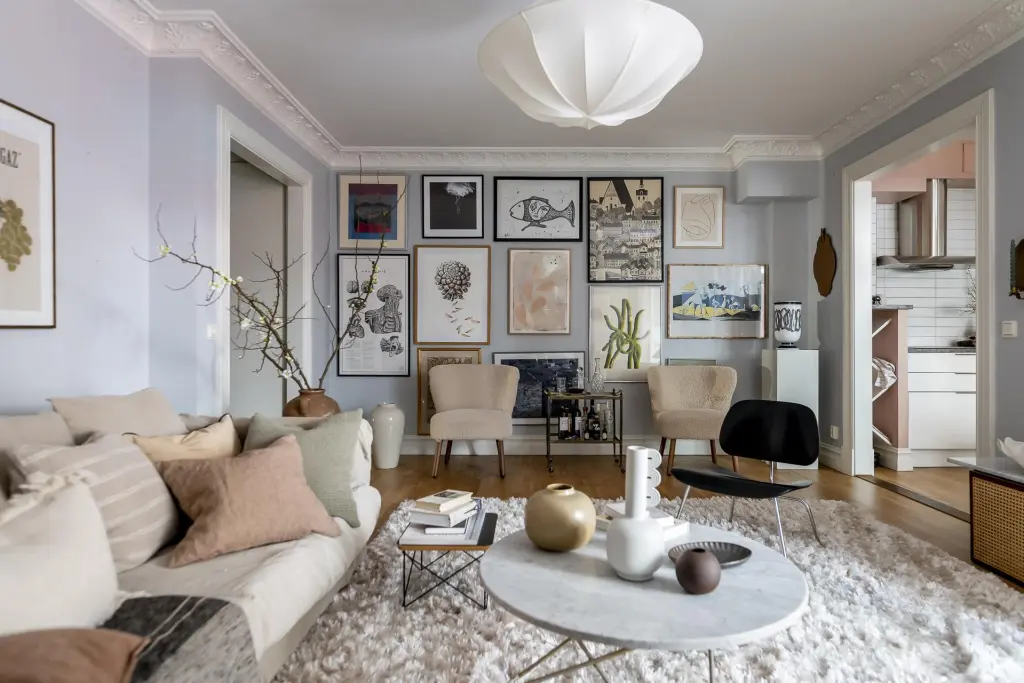 A grey living room with wooden floor and rug on ir and frames on the wall 