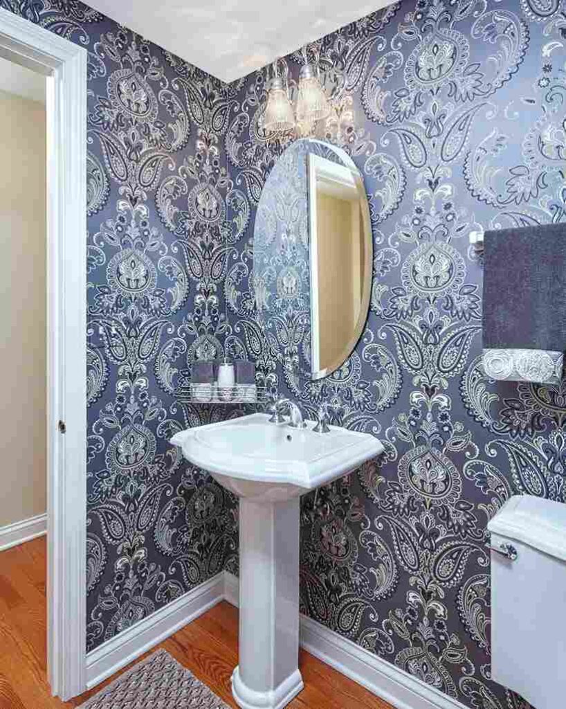 A grey and blue wallpaper and mirror on the wall 