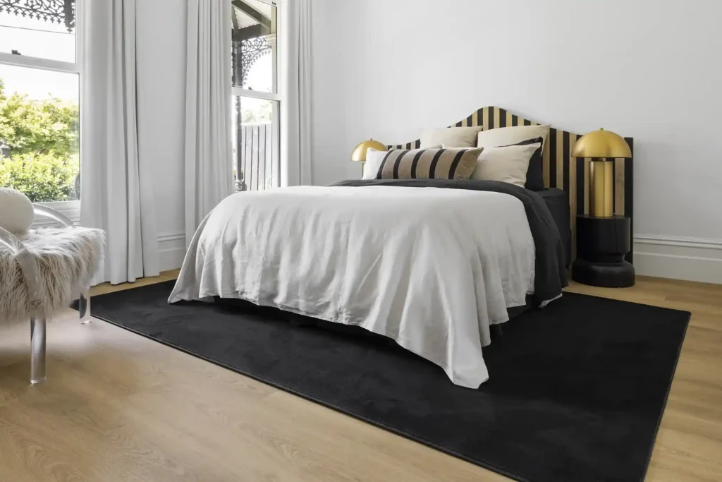A black rug on the wooden floor in grey bedroom and grey curtains