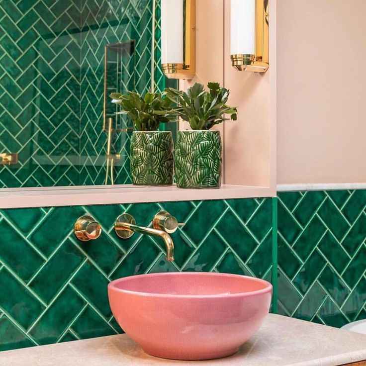 A green bathroom with pink basin with gold fixture