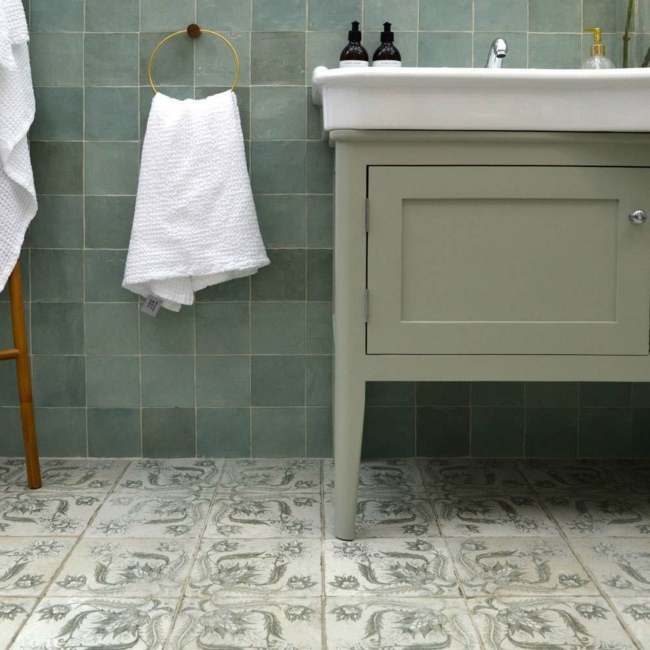 A green bathroom with mosaic tile and gold hang towel