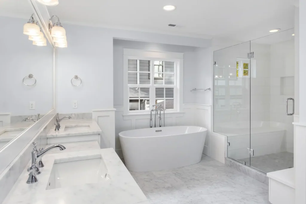 A bathroom with two bath area and white sink and window and lass shower area 