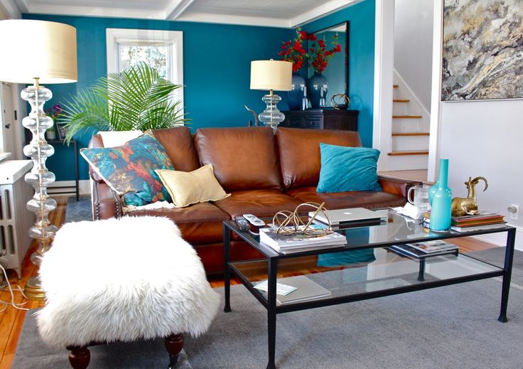 A teal blue living room with brown sofa and cushion with table 