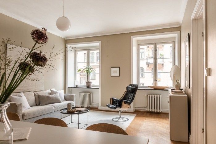 A sandy living room with windows and sofa with pillow and wooden floor 