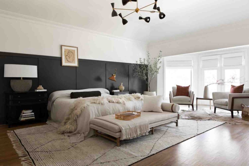 A half wall wainscoting wall in bedroom with windows and chair and wooden floor and rug on it 