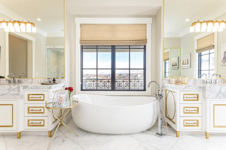 A white bathroom with gold trim and window 