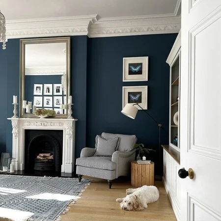 A white fireplace with blue living room with wooden floor and grey chair 