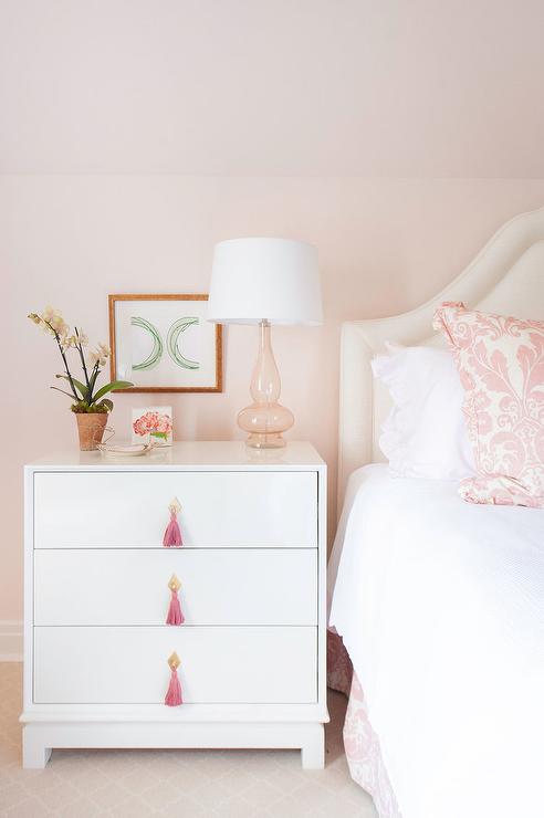 A pink bedroom with white side table  with pink accents 