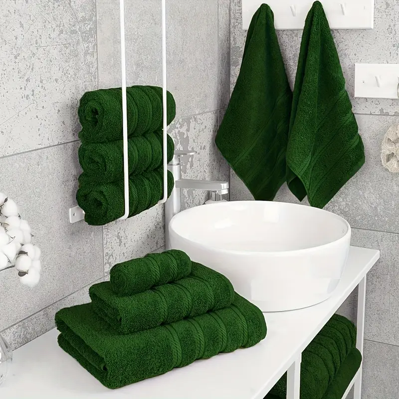 A white towel rack with green towel and and white sink