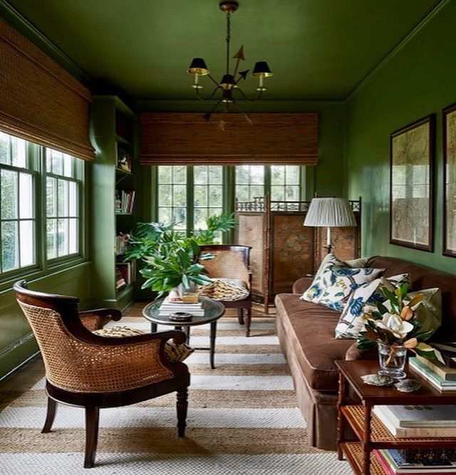 A sage green living room with windows treatment and chair and table 