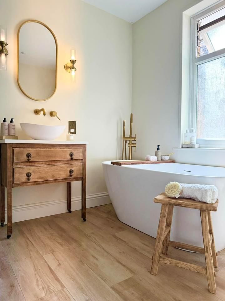 A white bathroom with white bathtub and gold accent 