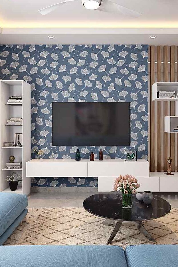 A living room with art and tv on the wall and shelves and table 