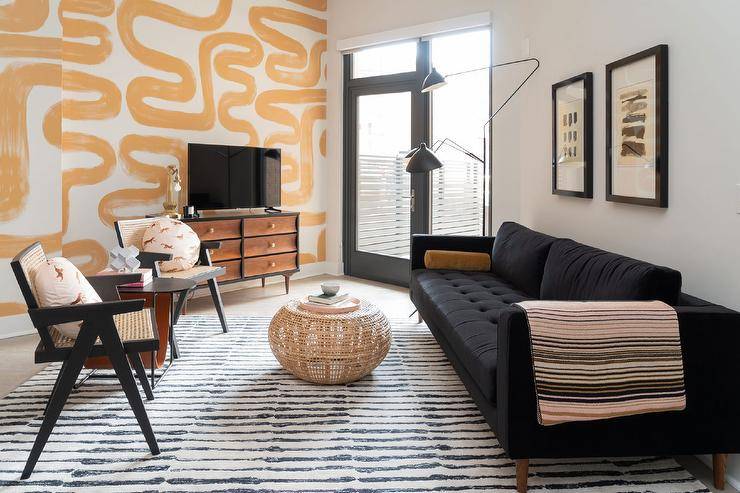 A small living room with black sofa and tv on cabinet and glass windows and black frames 