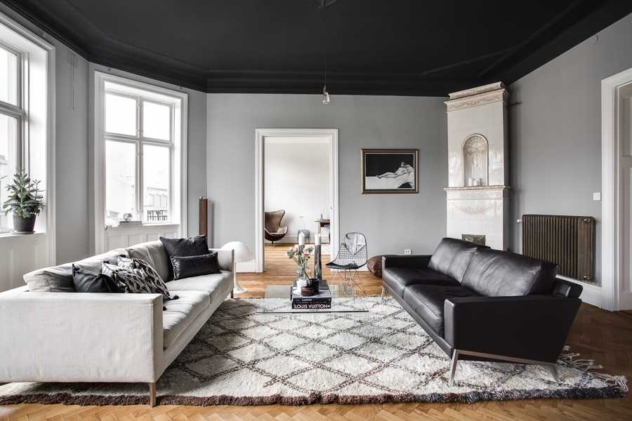 A grey and white living room with black celling and sofa and white sofa with cushion