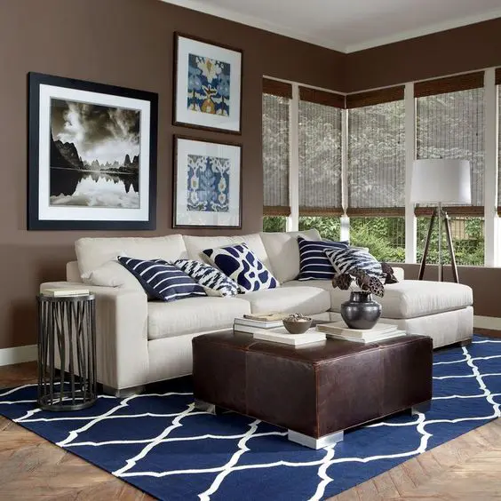 A brown living room with sofa with blue cushion and rug and wooden floor 