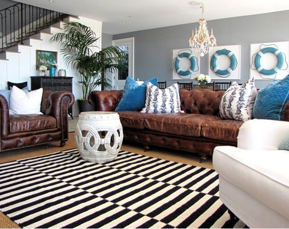 A grey living room with blue painting on the wall and brown sofa and wooden floor and rug on it 