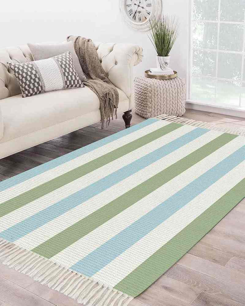A blue, green and white striped rug on wooden floor 