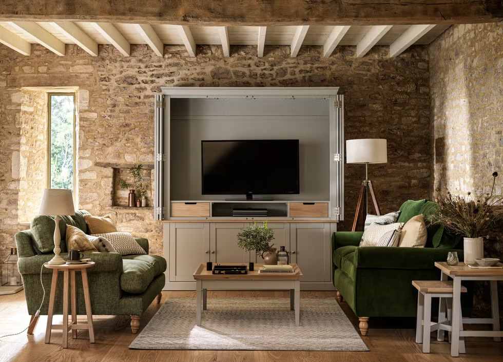 A brick living room with grey tv and green sofa with  beige cushion 