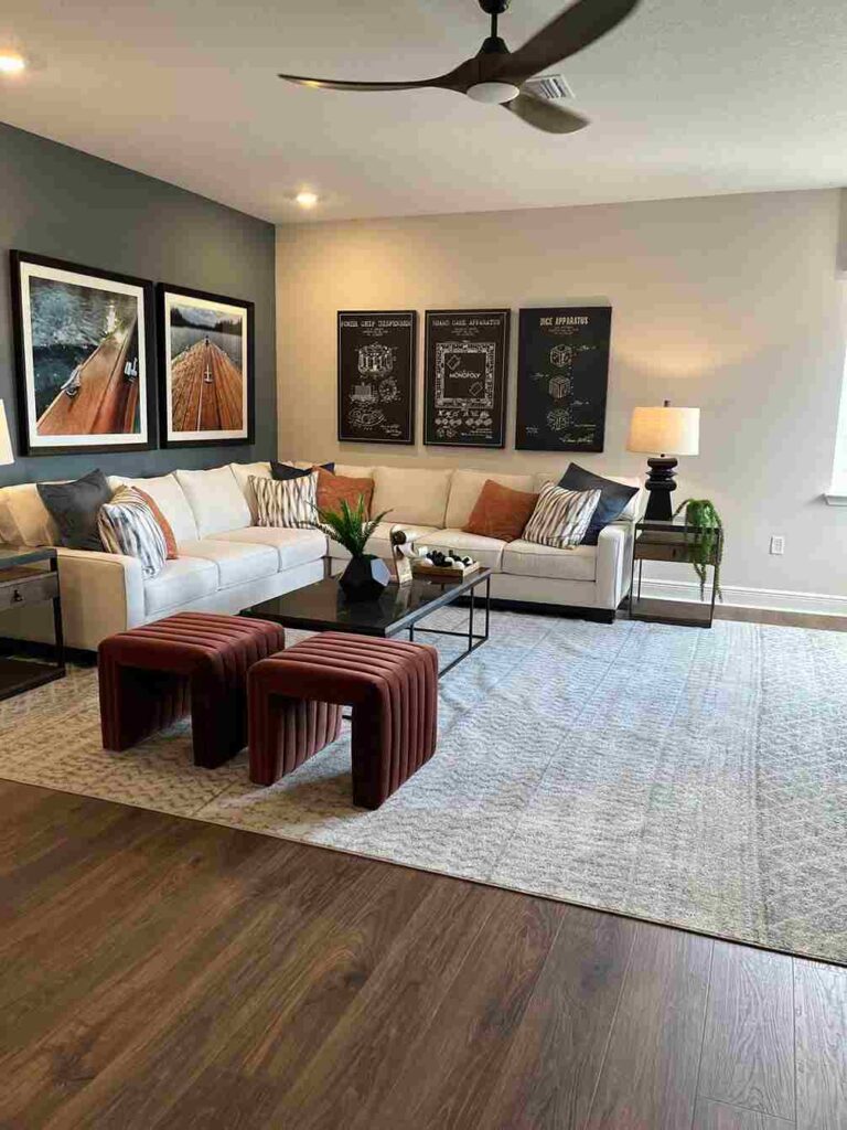 A grey and off white living room with frames on the wall and sofa with cushion and rug on the wooden flor