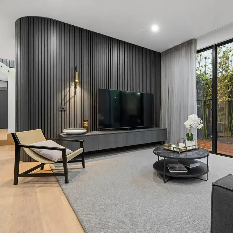 A grey living room with dark grey panel wall and wooden floor and rug on it 