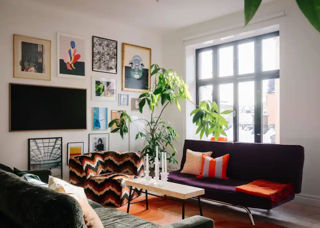 A tv wall with frames and windows and sofa with cushion 