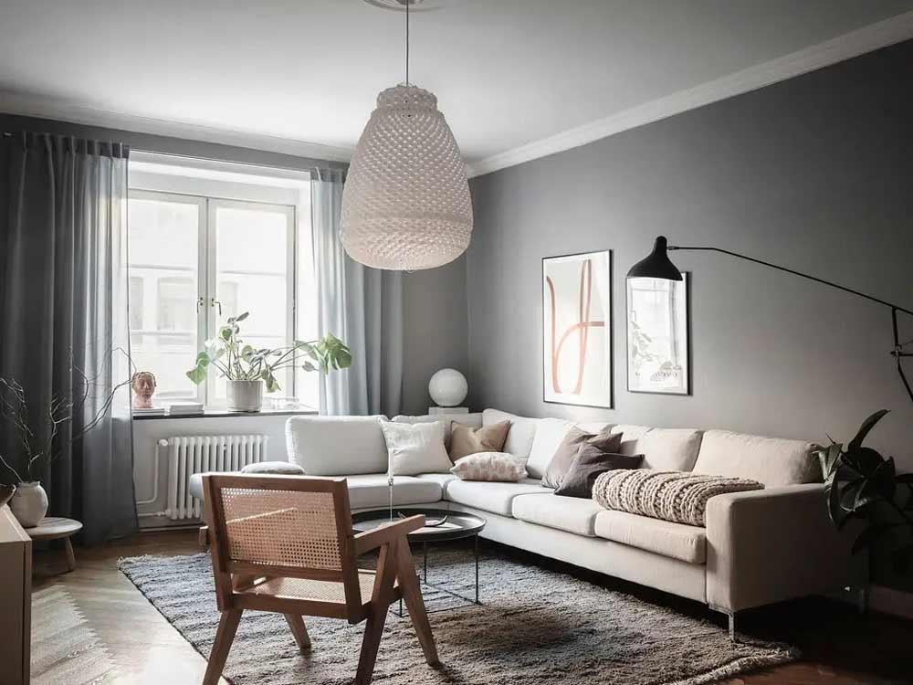 A grey living room with beige sofa with cushion and windows and curtain 