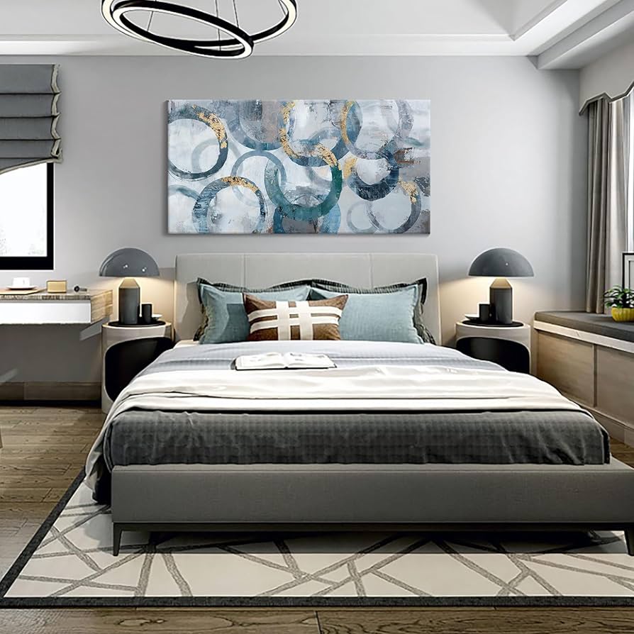 A grey living room with artwork on the floor and lamp on the side table 