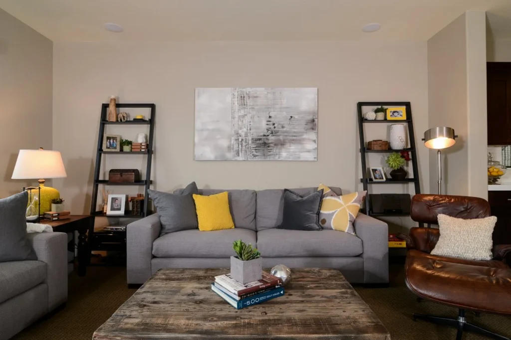 A beige living room with yellow cushion on grey sofa 