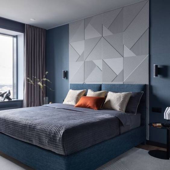 A navy blue bedroom with grey accents wall and blue bed with pillow and cushion 