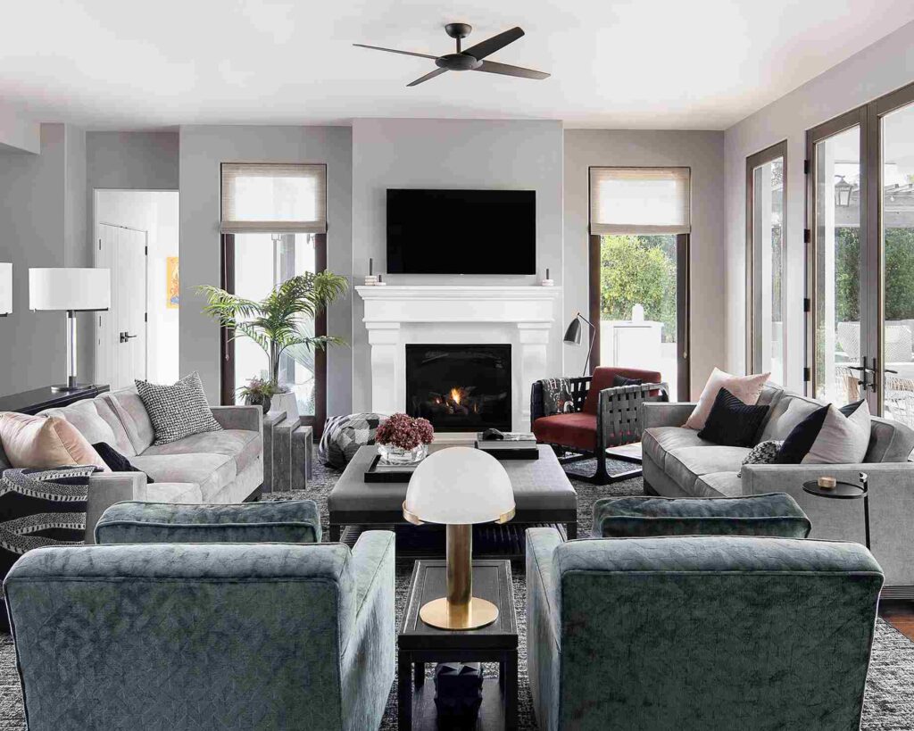 A small living room with opposite seating and tv on the wall and windows 