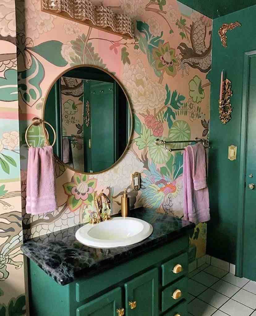 A green vanity in pink bathroom with white sink and gold fixture