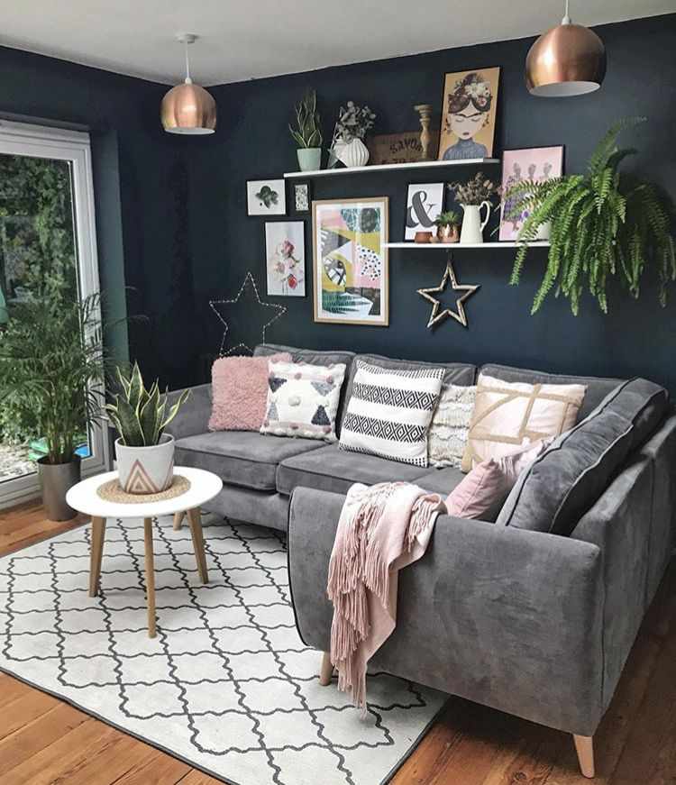 A grey and navy living room with plants in the room ad wooden floor and rug on it 