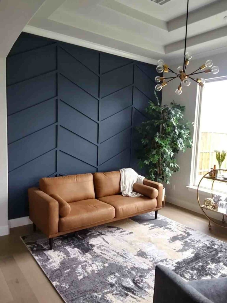 A grey and navy living room with tan sofa and wooden floor and rug on it 