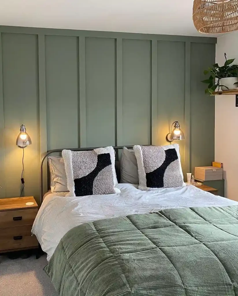 A sage green panel wall and lights and wooden floor and nightstand 