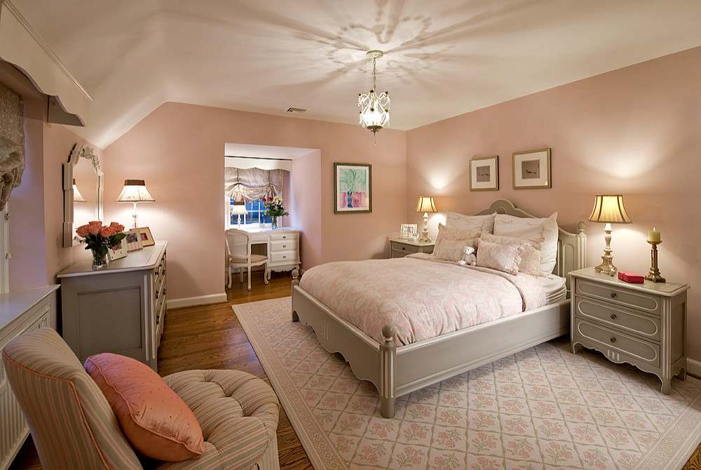 A white and pink bedroom with wooden floor and nightstand with lamp